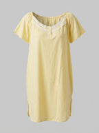 A pale yellow short-sleeve nightgown with a scoop neckline and white lace trim, displayed against a solid gray background.