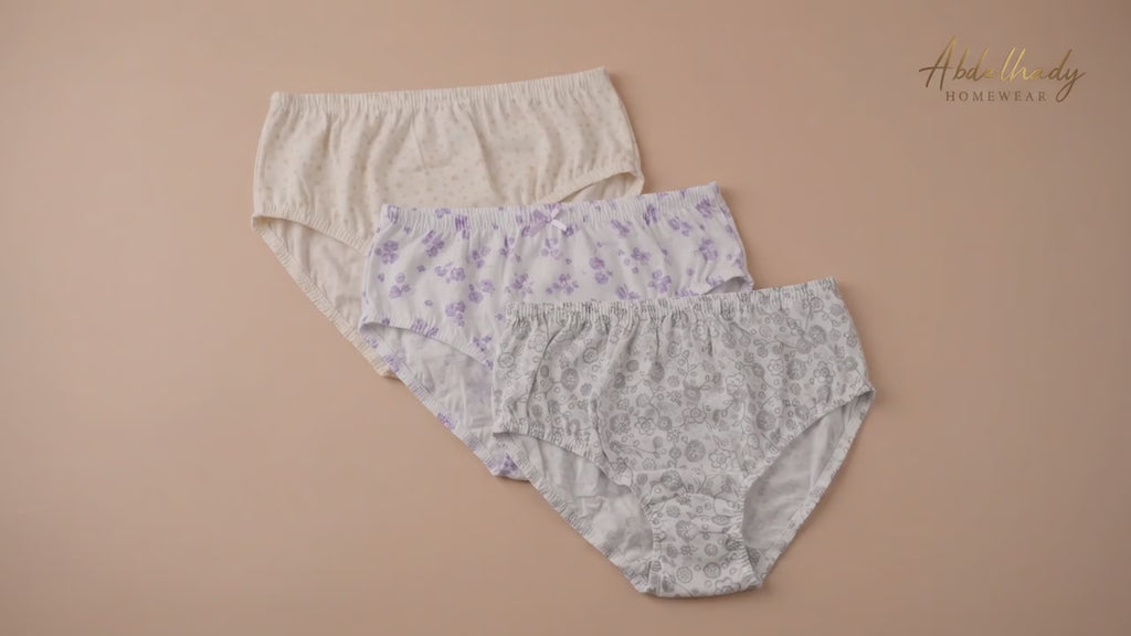 Three pairs of Abdelhady Homewear high-waisted cotton briefs with delicate floral and star patterns, laid flat on a peach background.